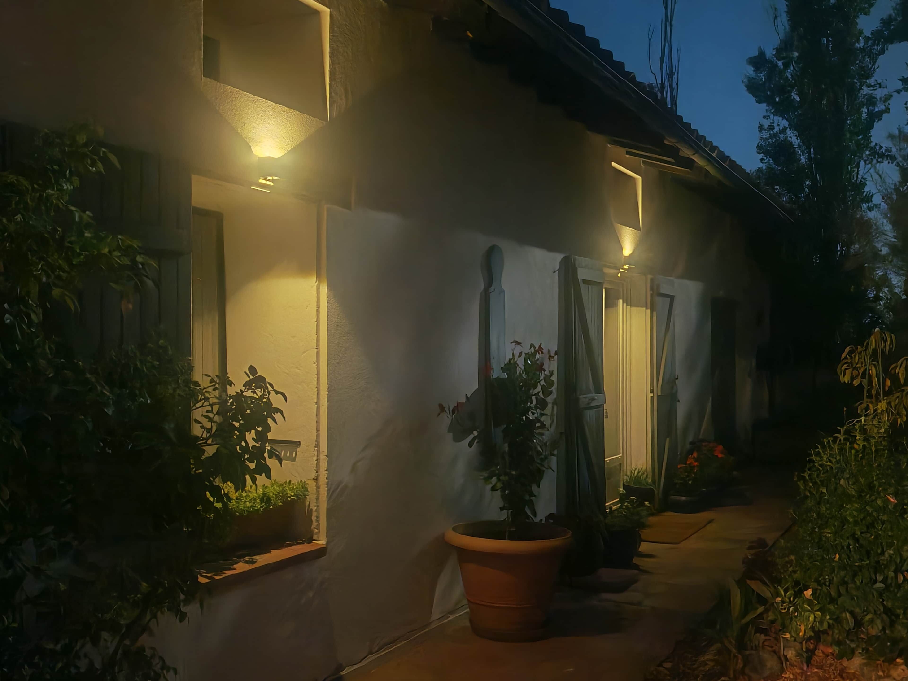 Un bâtiment doté d’un éclairage extérieur, de plantes en pot et d’une entrée abritée.