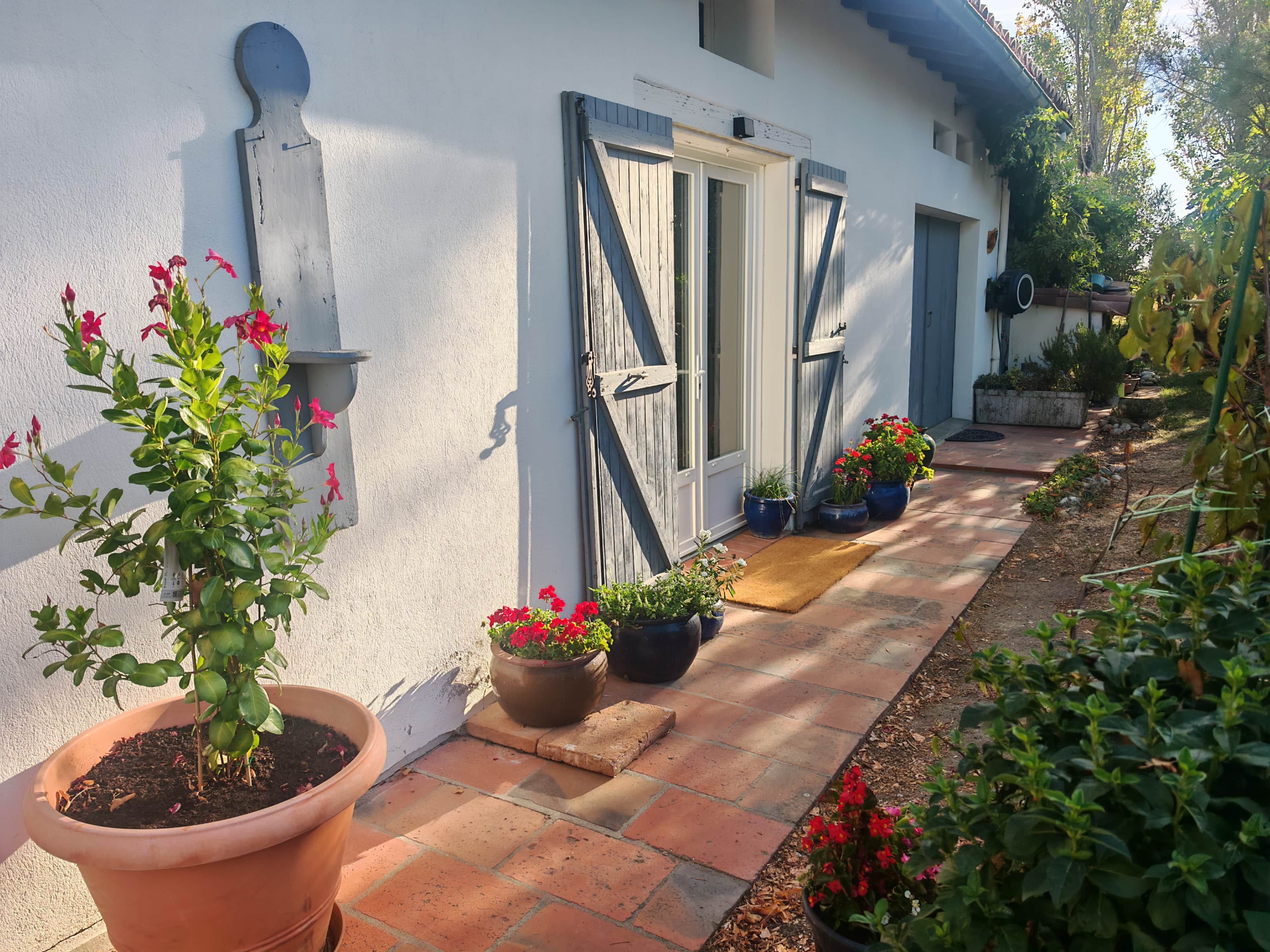 A house with a white exterior, a wooden door, and a pathway leading to the entrance.