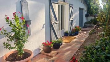 A house with a white exterior, a wooden door, and a pathway leading to the entrance.