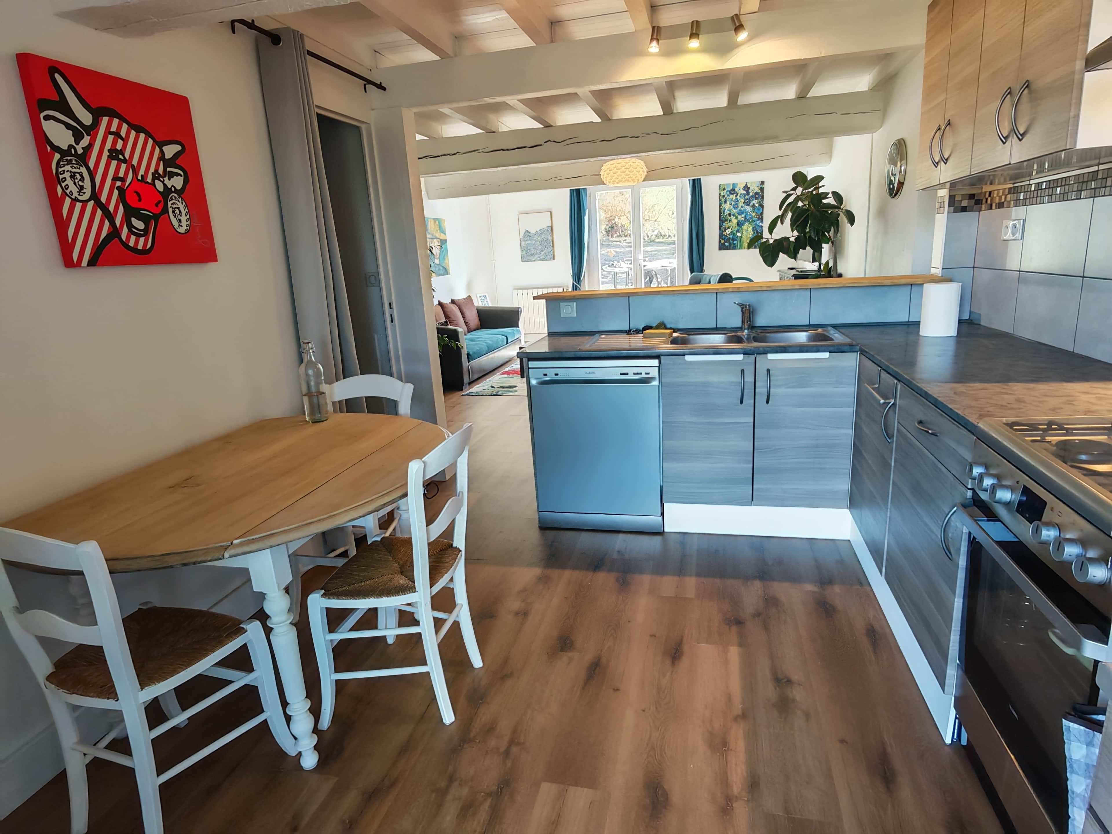 Eine moderne Küche mit einem Holztisch, weißen Stühlen und Edelstahlgeräten.