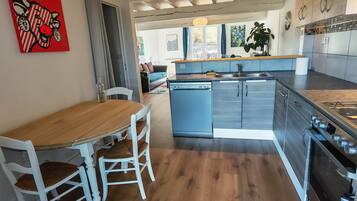 Una cocina moderna con una mesa de comedor de madera, sillas blancas y electrodomésticos de acero inoxidable.