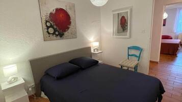 A bedroom with a bed, bedside tables, a chair, and artwork on the walls.