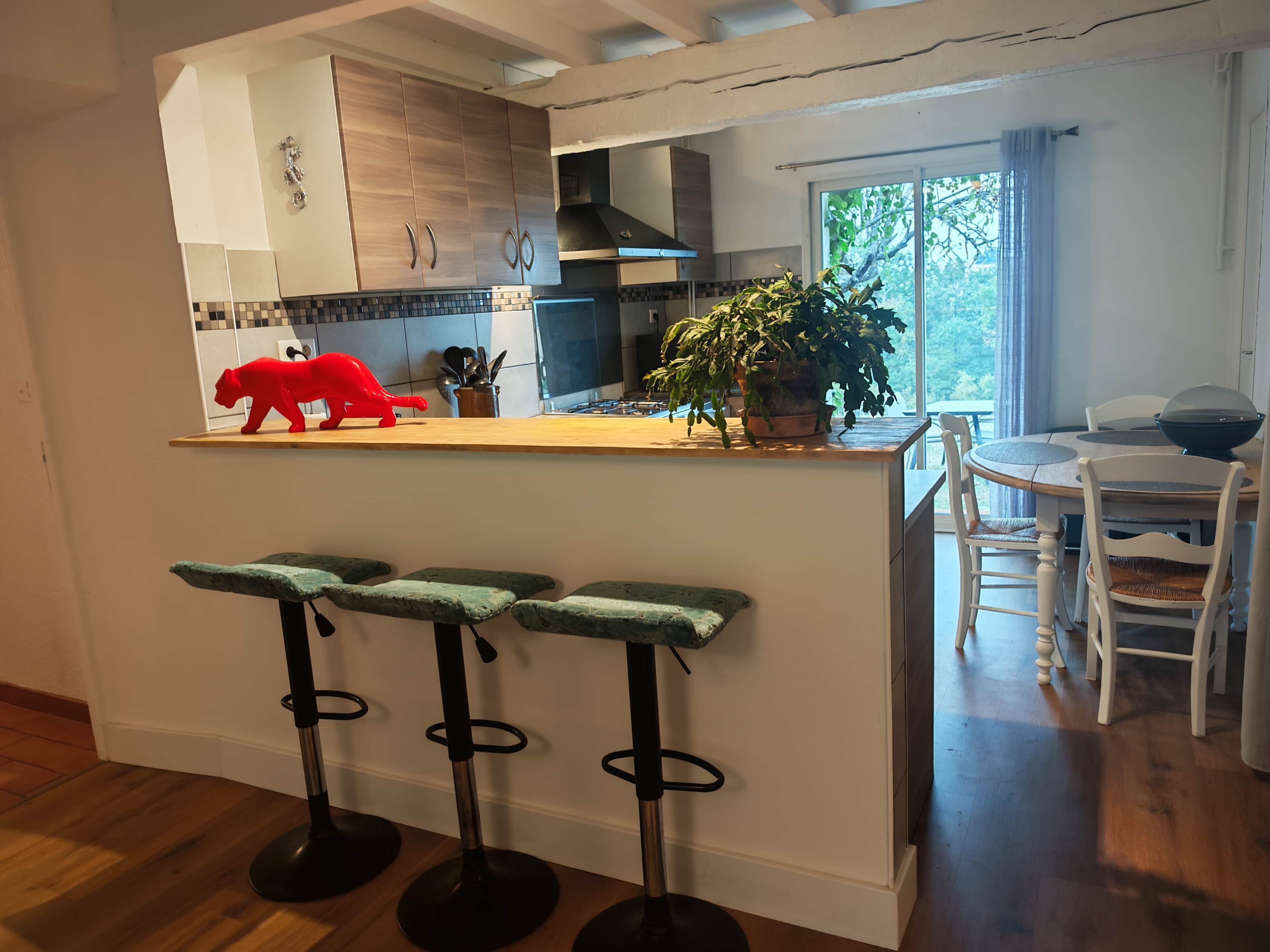 A modern kitchen with a wooden countertop, bar stools, and a dining area with a table and chairs.