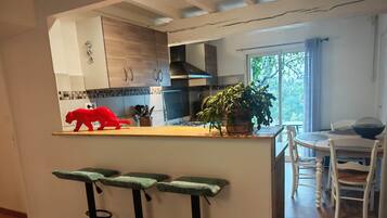 A modern kitchen with a wooden countertop, bar stools, and a dining area with a table and chairs.
