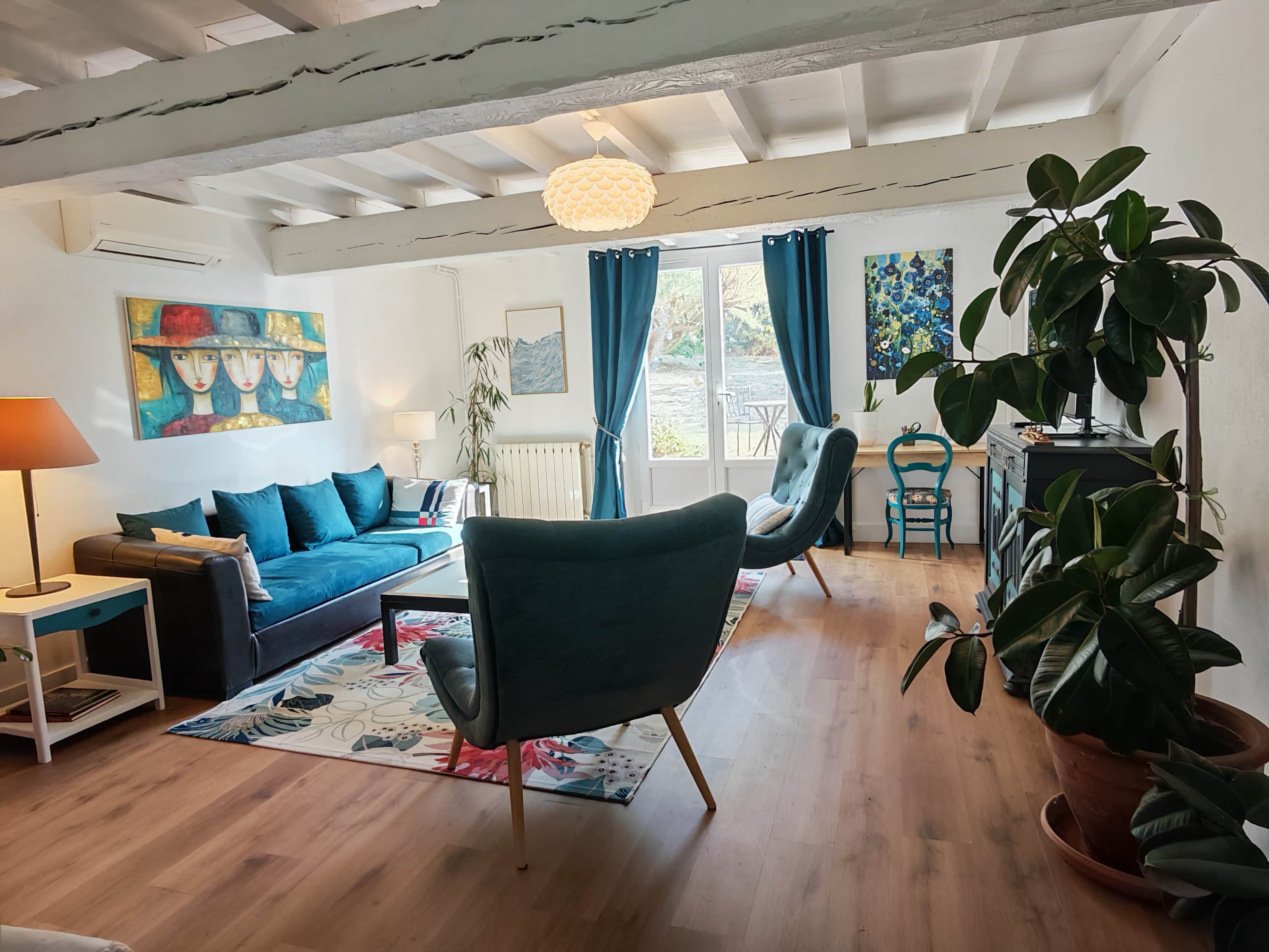A living room with a sofa, armchair, and potted plants.