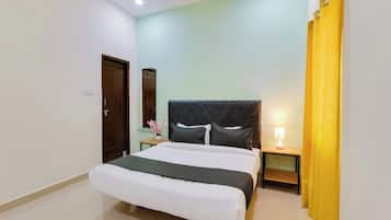 A hotel room with a bed, a nightstand, a lamp, a mirror, and a curtain.