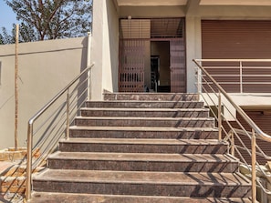 A set of outdoor stone steps leading to a gated entrance, with metal railings on both sides. - Super Collection O RBS Classic Stay  (Hyderabad)