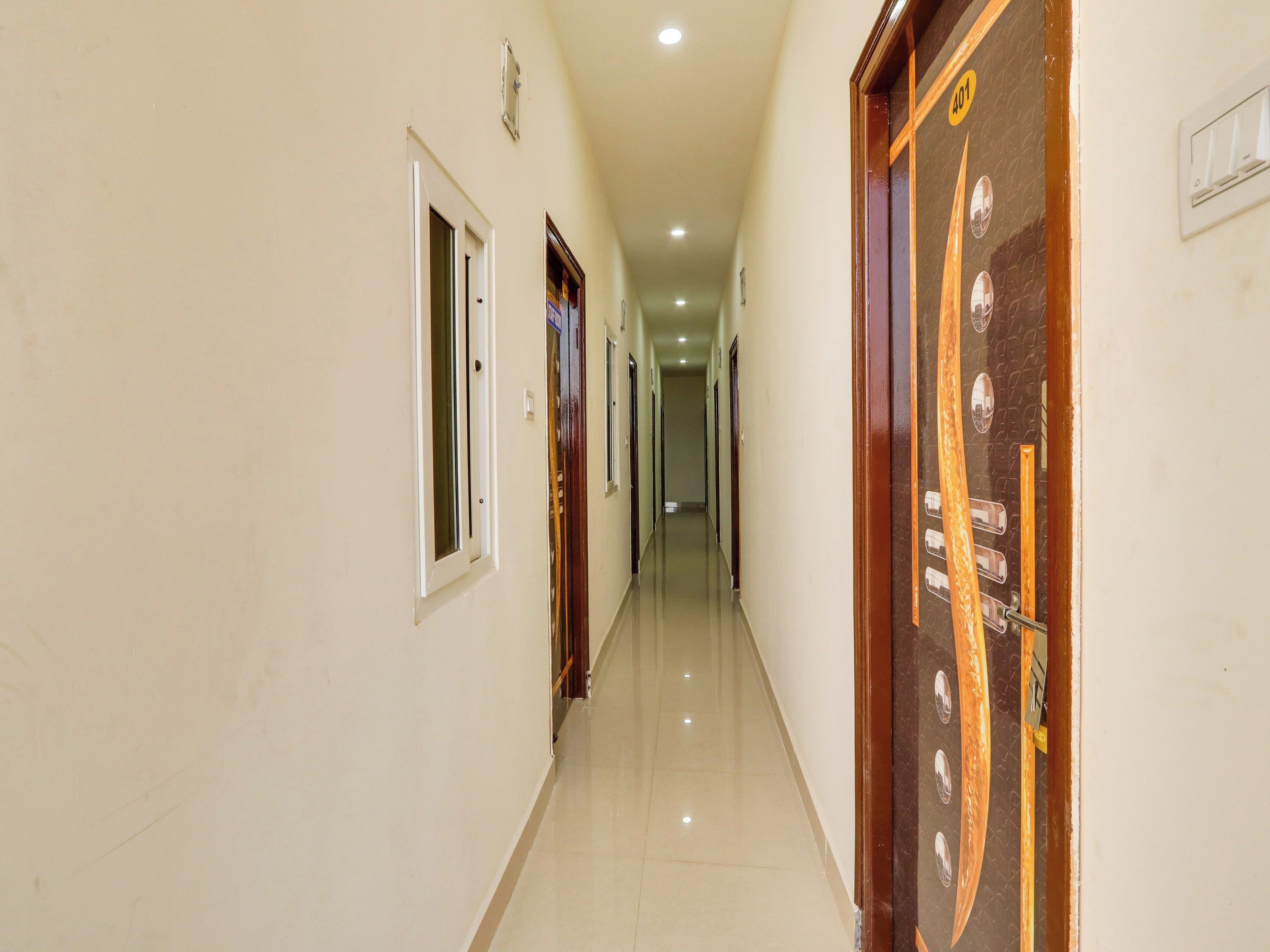 A corridor with doors on both sides, a tiled floor, and a ceiling with recessed lighting.
