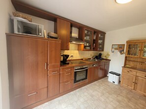A kitchen with wooden cabinets, a microwave, a stove, and a sink. - Enjoy a relaxing vacation at the DEICHSTERN vacation home in Butjadingen (Butjadingen)