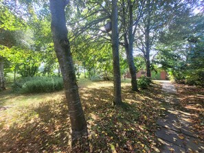 A pathway surrounded by trees and a brick building in the background. - Enjoy a relaxing vacation at the DEICHSTERN vacation home in Butjadingen (Butjadingen)