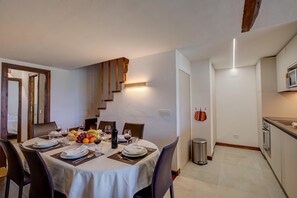 A dining area with a table set for four, a kitchen with modern appliances, and a staircase leading to another level. - Home Suite Grange (Sauze di Cesana)