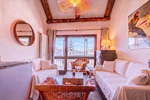 Una habitación acogedora con chimenea, un ventanal con vistas a las montañas y un comedor con mesa y sillas.