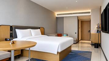 Une chambre d’hôtel moderne équipée d’un lit, d’une table de chevet et d’un téléviseur fixé au mur.
