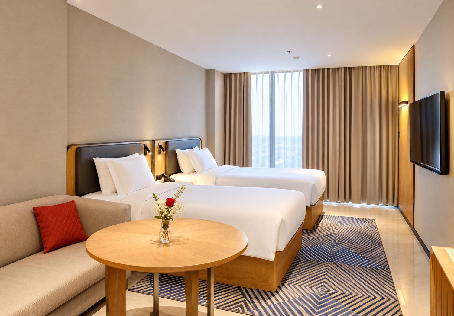 Une chambre d’hôtel avec deux lits, un canapé, une table ronde et un téléviseur.