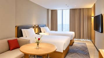 Une chambre d’hôtel avec deux lits, un canapé, une table ronde et un téléviseur.