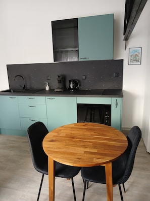 Eine moderne Küche mit türkisfarbenen Schränken, einer schwarzen Arbeitsplatte und einem Esstisch aus Holz mit schwarzen Stühlen.
