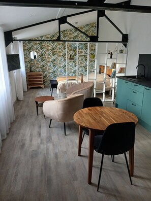Ein modernes Interieur mit Essbereich, einer Couch und einer Küche mit Türkis-Schränken.