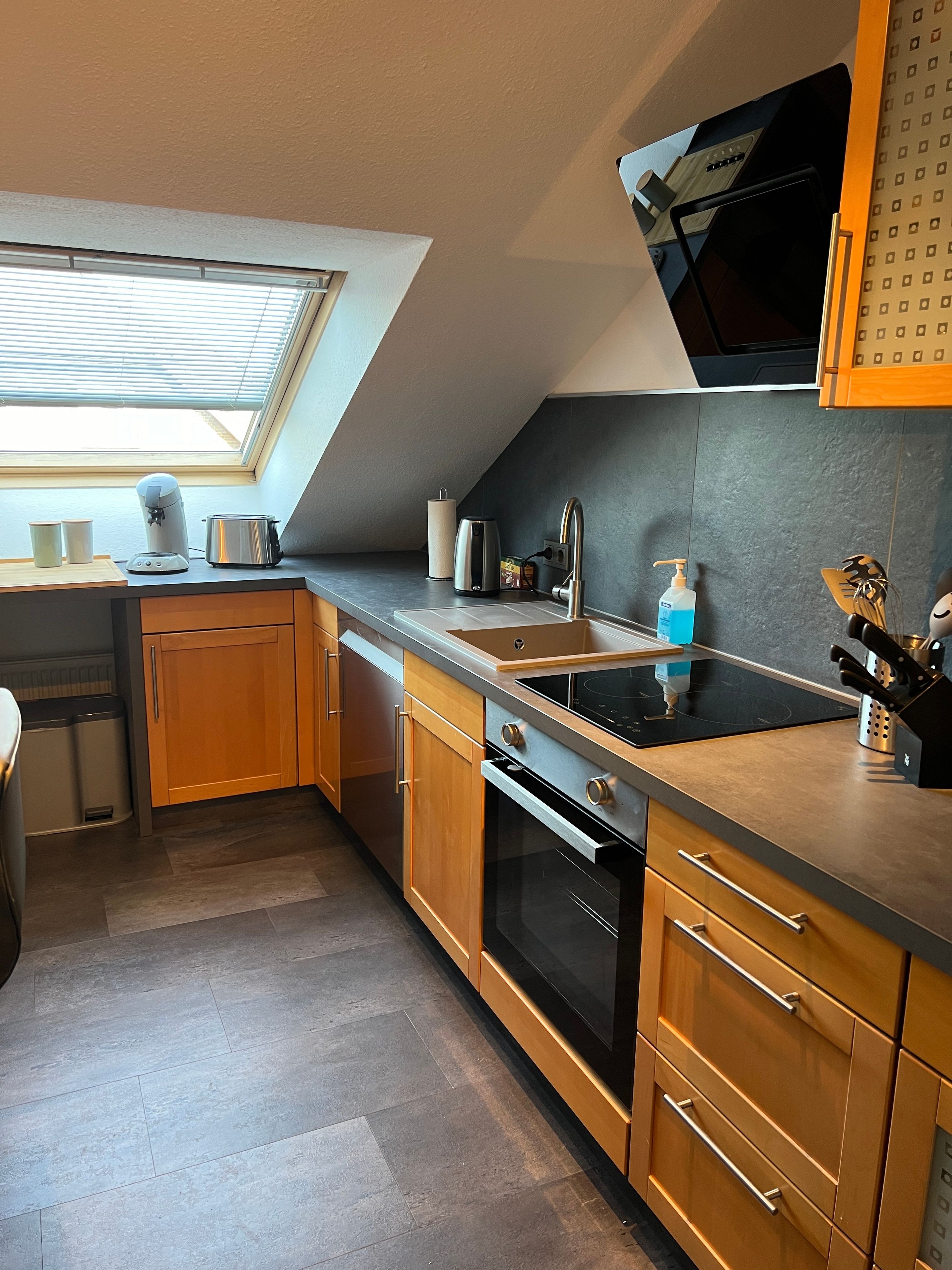 Eine moderne Küche mit Oberlicht, eingebautem Backofen und einer schwarzen Mikrowelle.