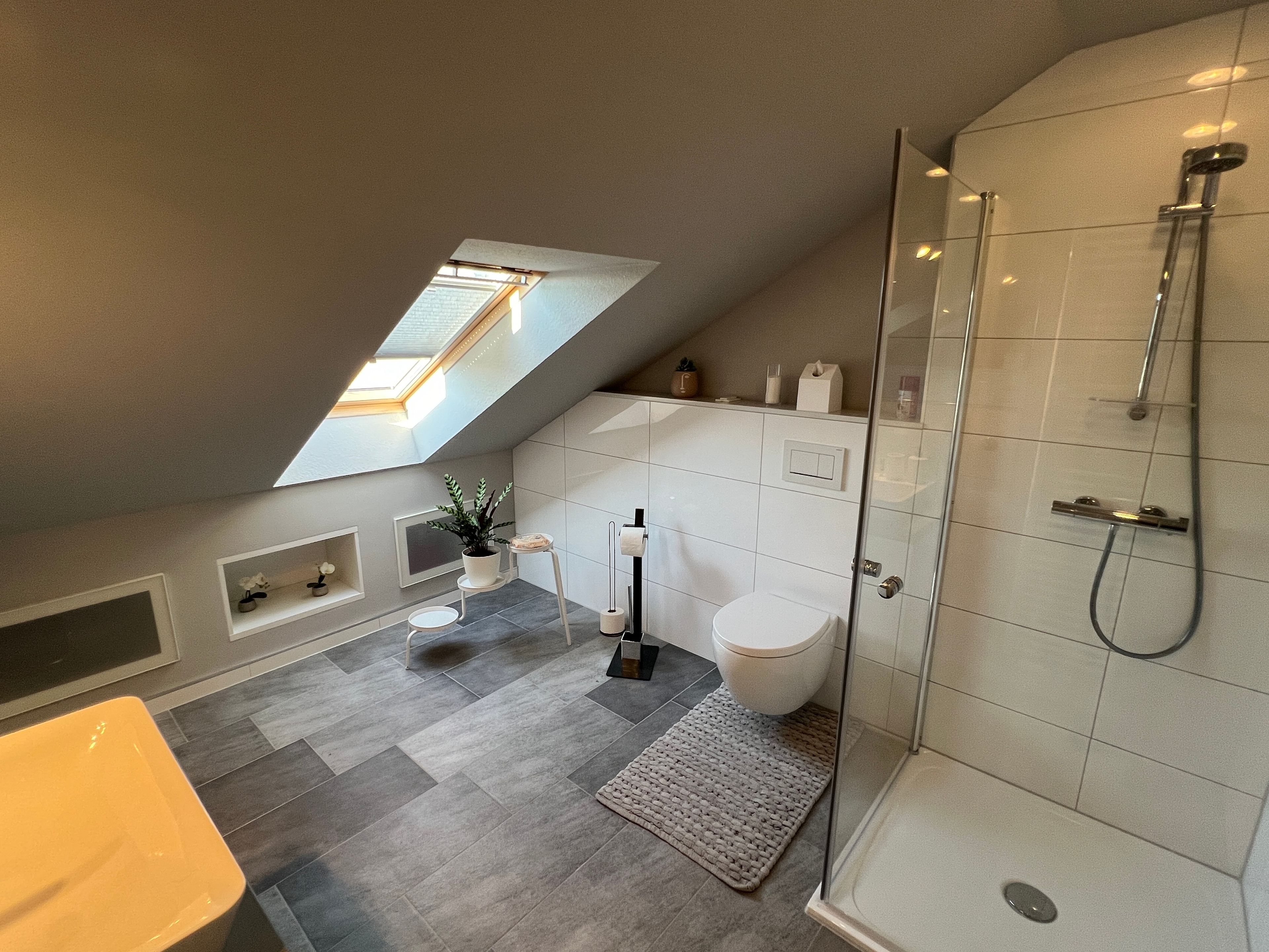 Ein modernes Badezimmer mit Oberlicht, Dusche und Toilette.