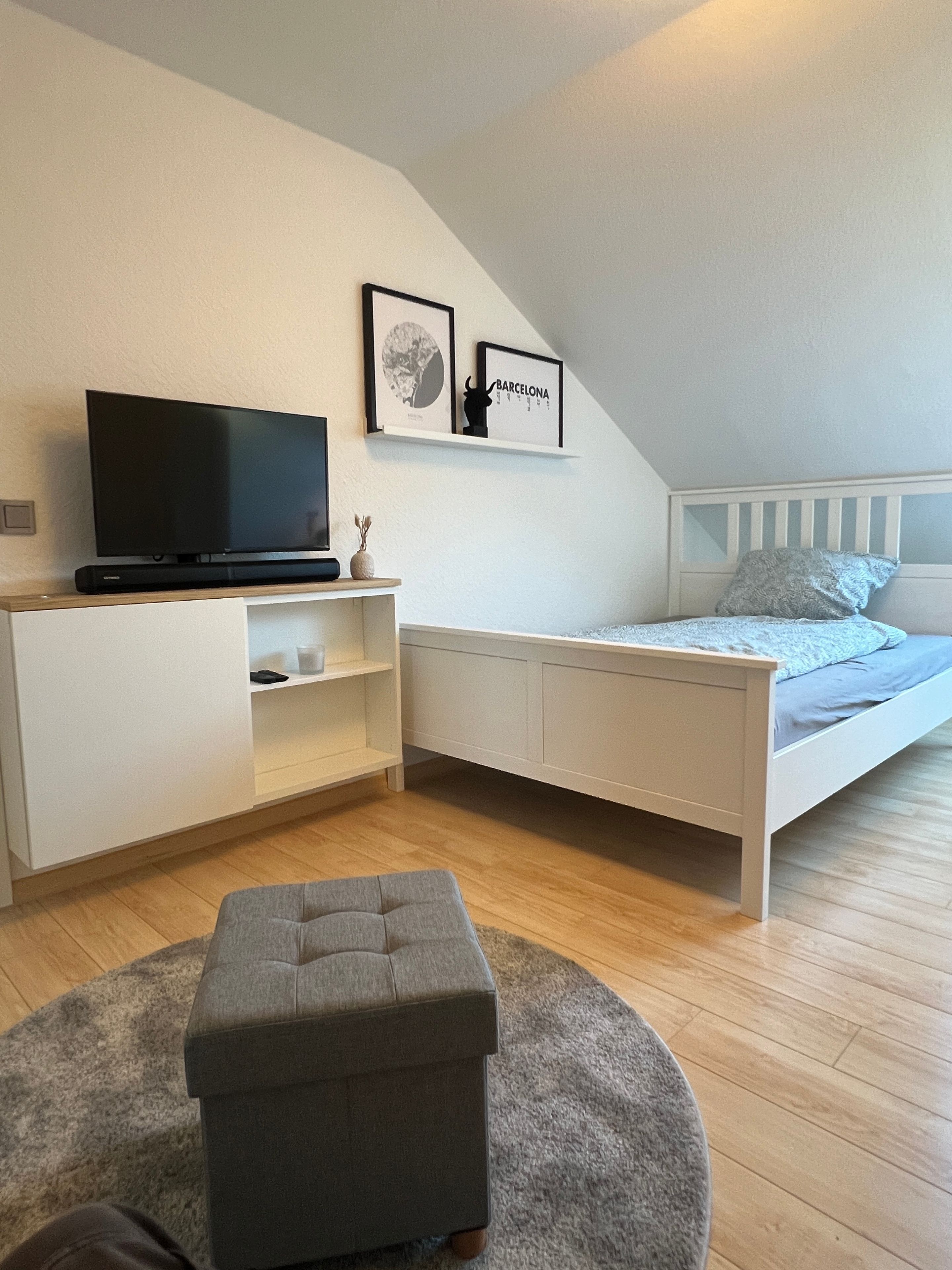 Ein Schlafzimmer mit einem Bett, einem Fernseher, einem Schreibtisch und einem Sessel.