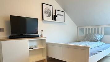 Ein Schlafzimmer mit einem Bett, einem Fernseher, einem Schreibtisch und einem Sessel.