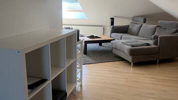 Ein modernes Wohnzimmer mit einem grauen Sofa, einer weißen Regaleinheit und Holzböden.
