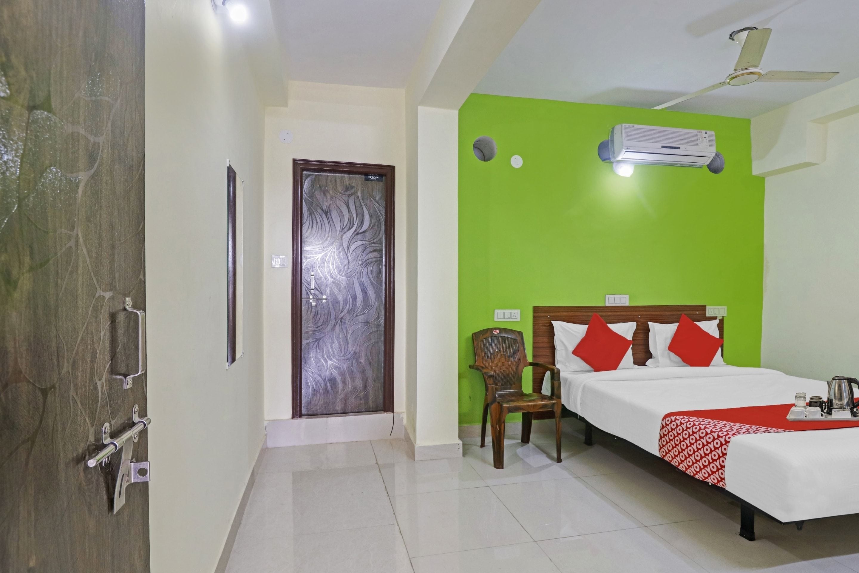 Una habitación de hotel con una cama, una silla, un armario, una puerta y un ventilador de techo.