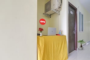 Una mesa de recepción con una computadora portátil, un florero con flores y un letrero con la marca 'OYO'.