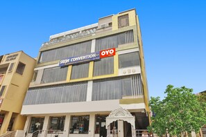 Un edificio de varios pisos con un cartel que dice 'Convention' y 'Oyo Rooms', indicando un hotel o centro de convenciones.