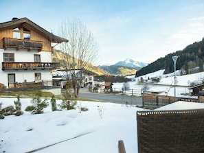 Schneebedeckte Landschaft mit einem Holzhaus, das Balkone hat, und einem Berg im Hintergrund.