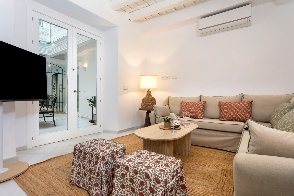 A modern living room with a flat-screen TV, a sofa set, a coffee table, and a lamp.