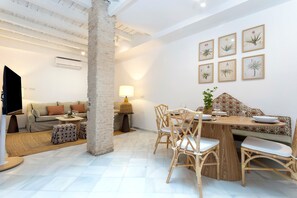 A modern living space with a sofa, dining table, chairs, and a TV. - Genteel Home Patio del Arenal (Seville)