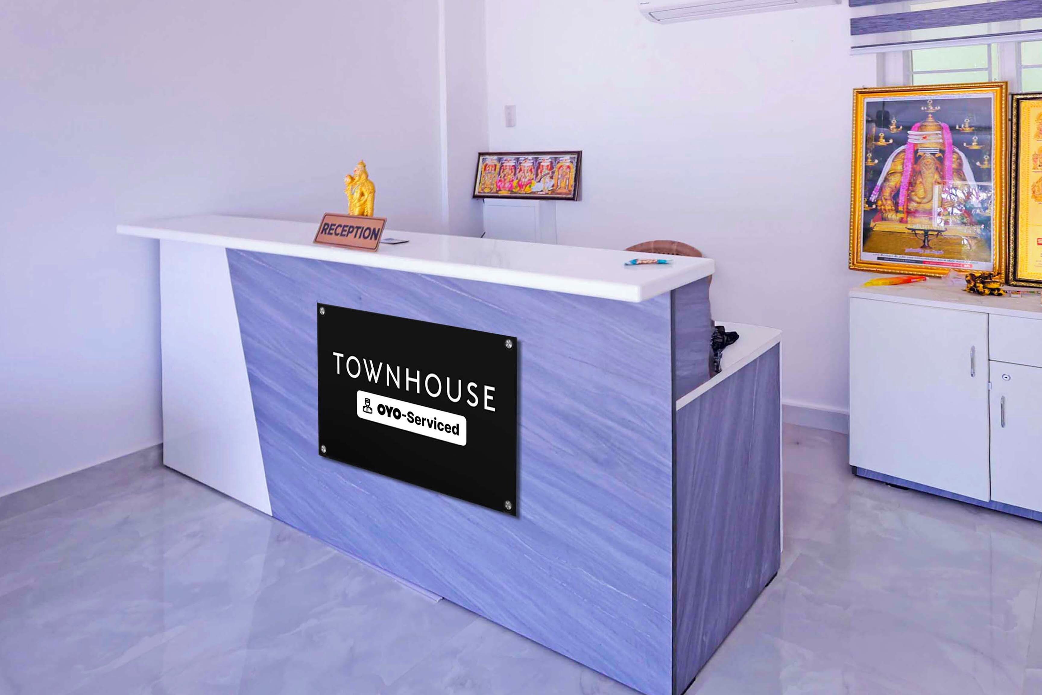 Un comptoir d’accueil portant l’inscription « TOWNHOUSE », avec une pancarte indiquant « Oyo-Serviced » et une petite statue posée sur le dessus.