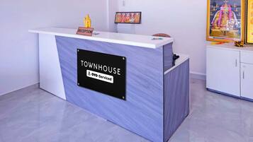 Un comptoir d’accueil portant l’inscription « TOWNHOUSE », avec une pancarte indiquant « Oyo-Serviced » et une petite statue posée sur le dessus.