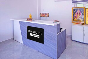 A reception desk labeled 'TOWNHOUSE' with a sign indicating 'Oyo-Serviced' and a small statue on top. - Townhouse Karumathampatti SBA's Park Inn (Sulur)