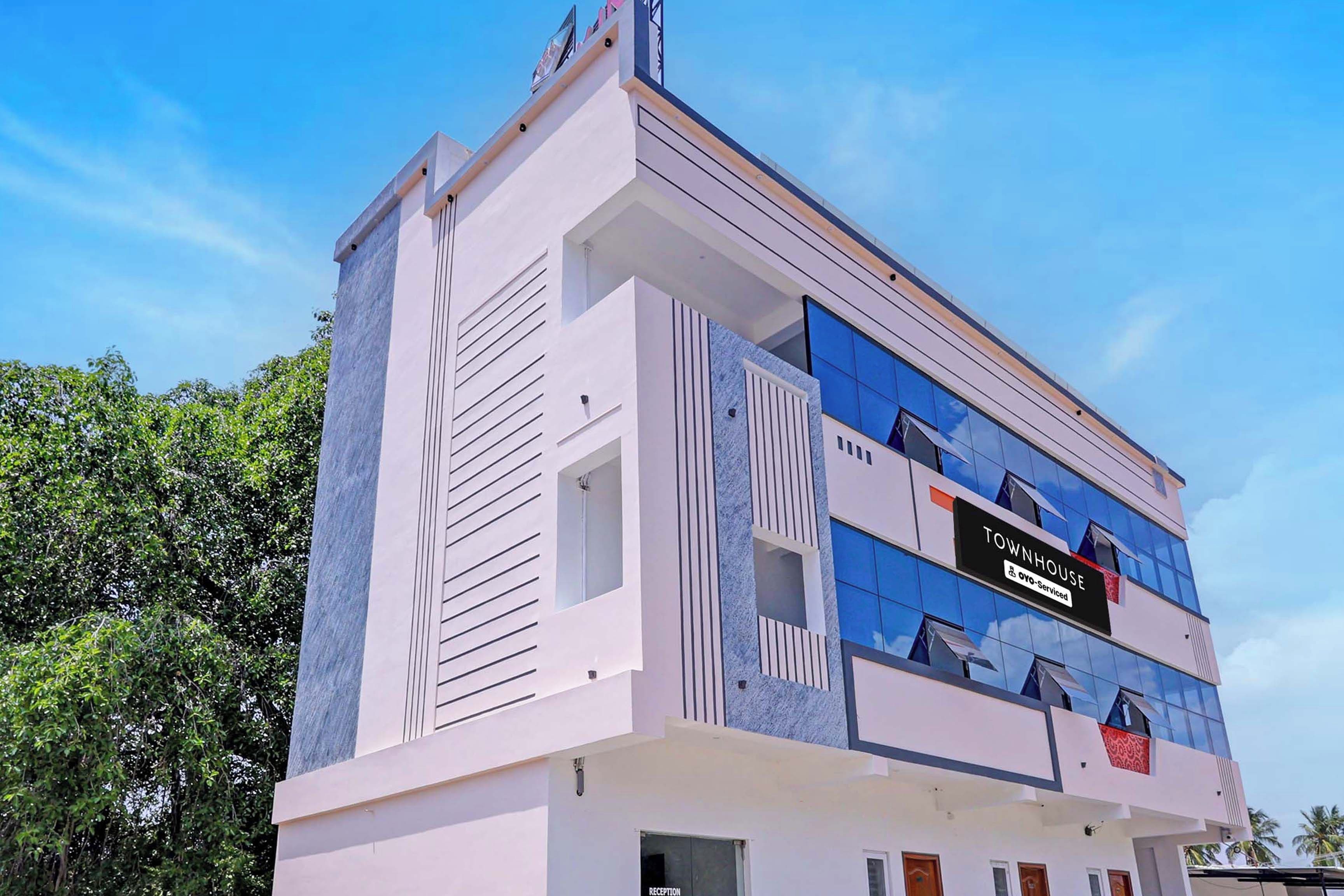 A modern townhouse with a prominent reception area, a sign indicating it is serviced by a specific company, and a clear view of the sky.