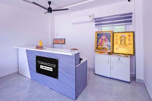 A reception desk with a sign indicating 'TOWNHOUSE OYO-Service' and a ceiling fan above.