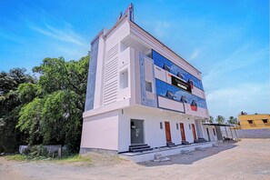 Un edificio de varios pisos con una recepción, un cartel que dice 'TOWNHOUSE' y un cielo despejado.