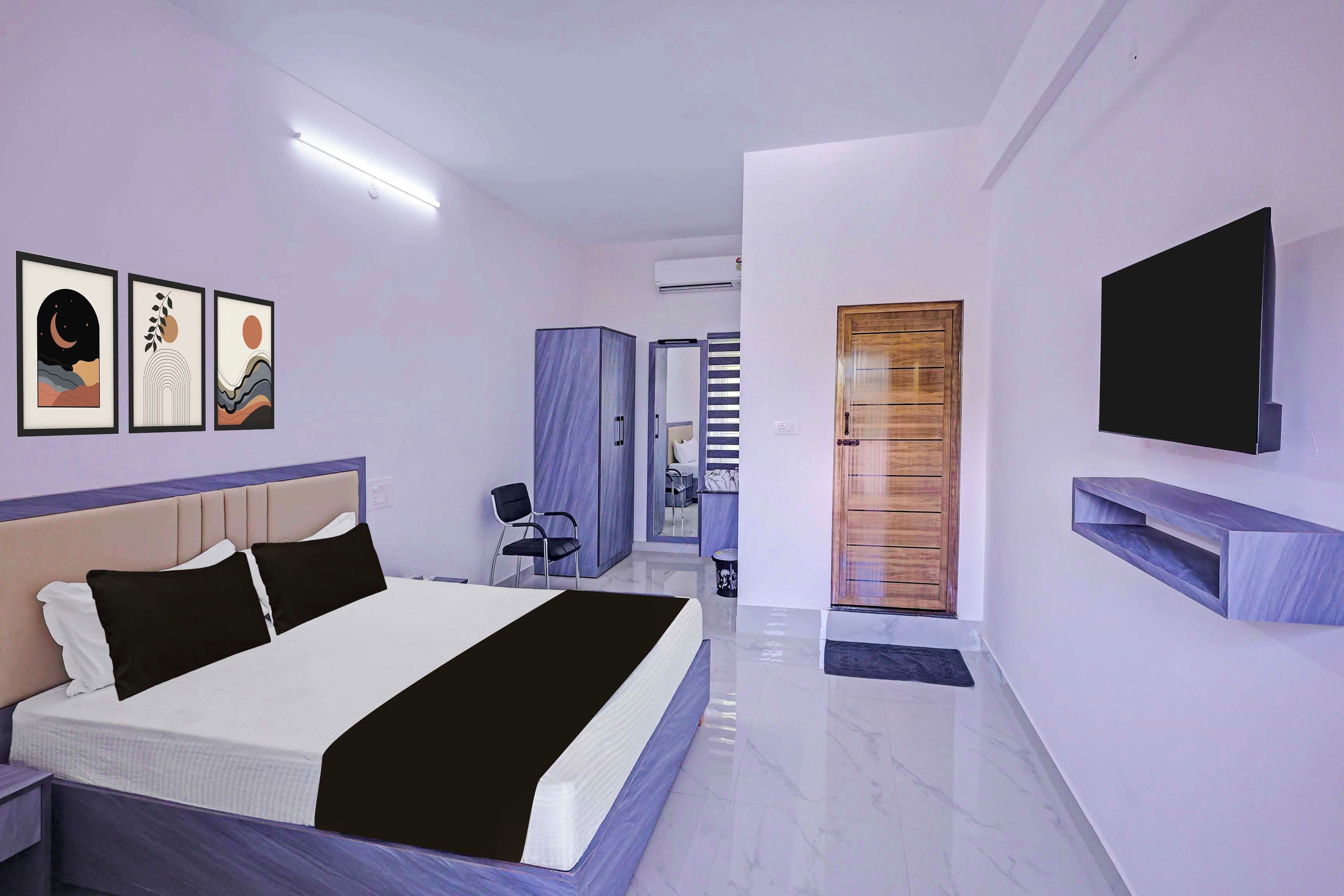 A modern bedroom with a bed, bedside tables, a TV, and artwork on the wall.