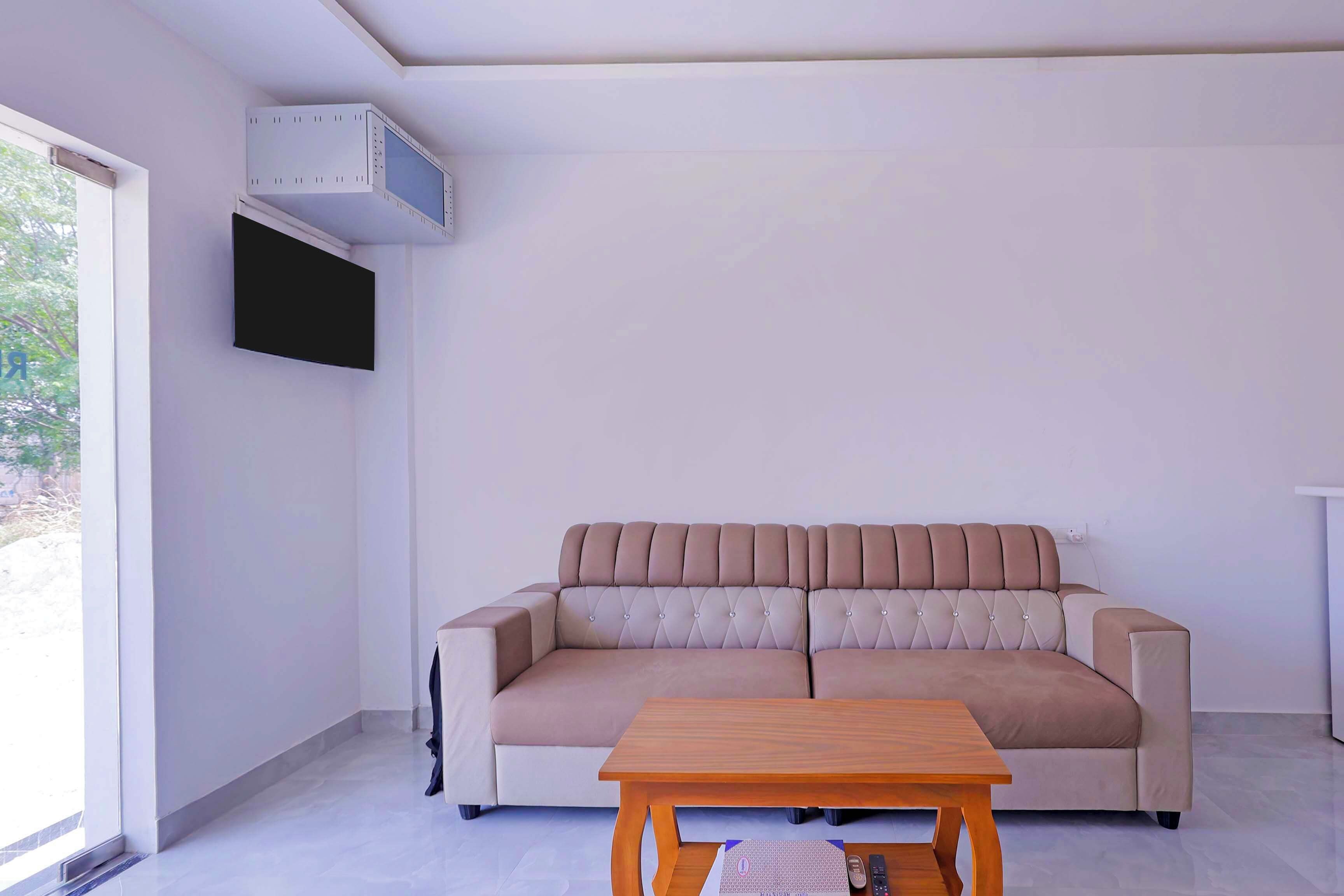 Una sala de estar moderna con un sofá color beige, una mesa de centro de madera y un televisor de pantalla plana montado en la pared.