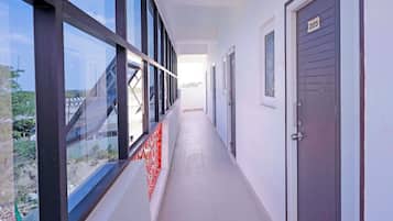 A corridor with large windows, a door marked with the number 205, and a patterned red barrier.