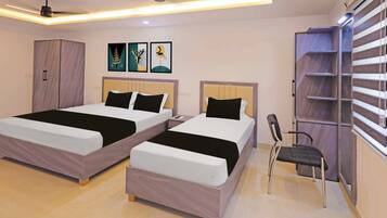 Una habitación de hotel con dos camas, un armario, una silla y obras de arte en la pared.
