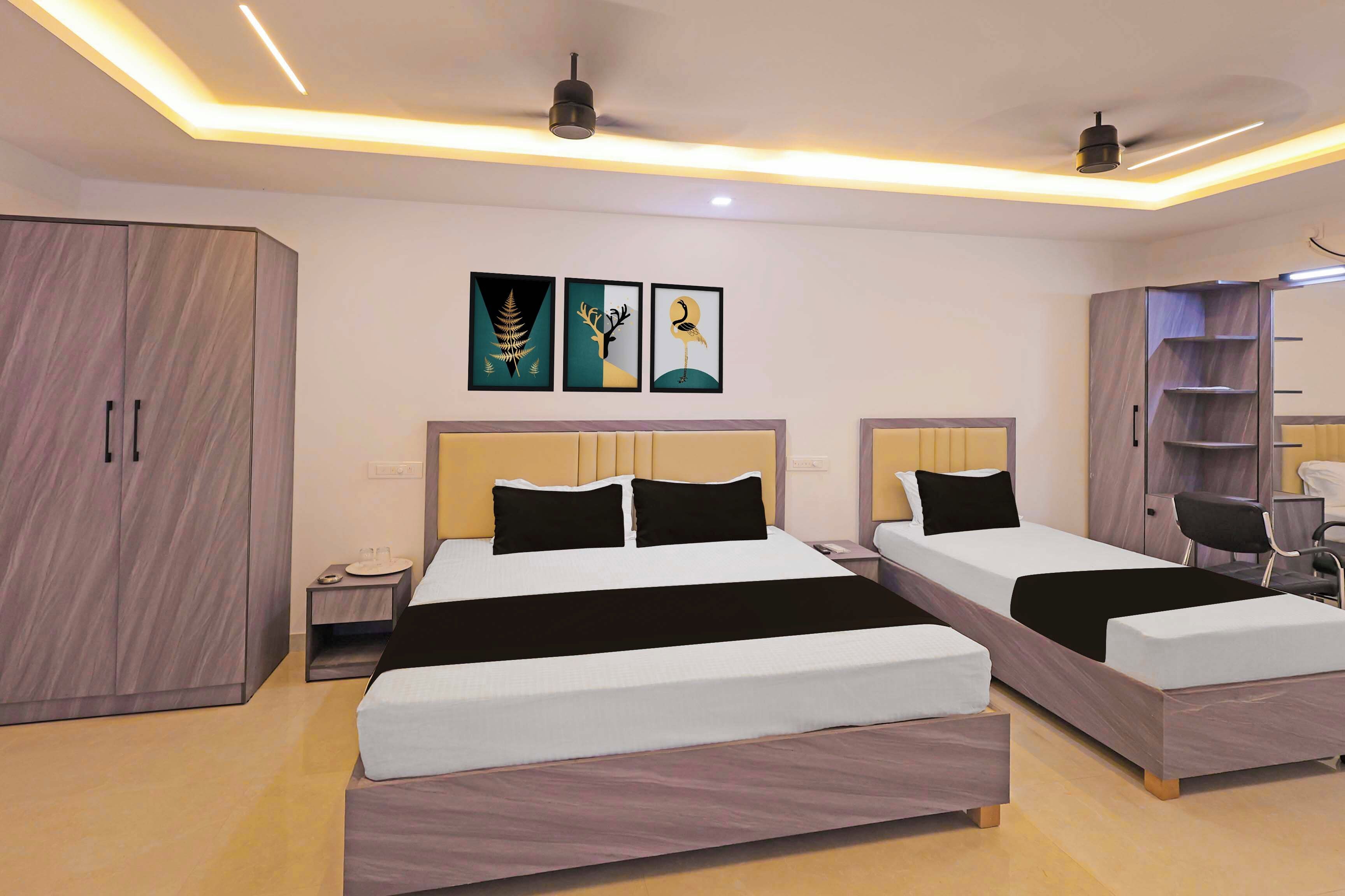 A hotel room with two beds, a wardrobe, a nightstand, and artwork on the wall.