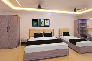Una habitación de hotel con dos camas, un armario, una mesita de noche y una obra de arte en la pared.