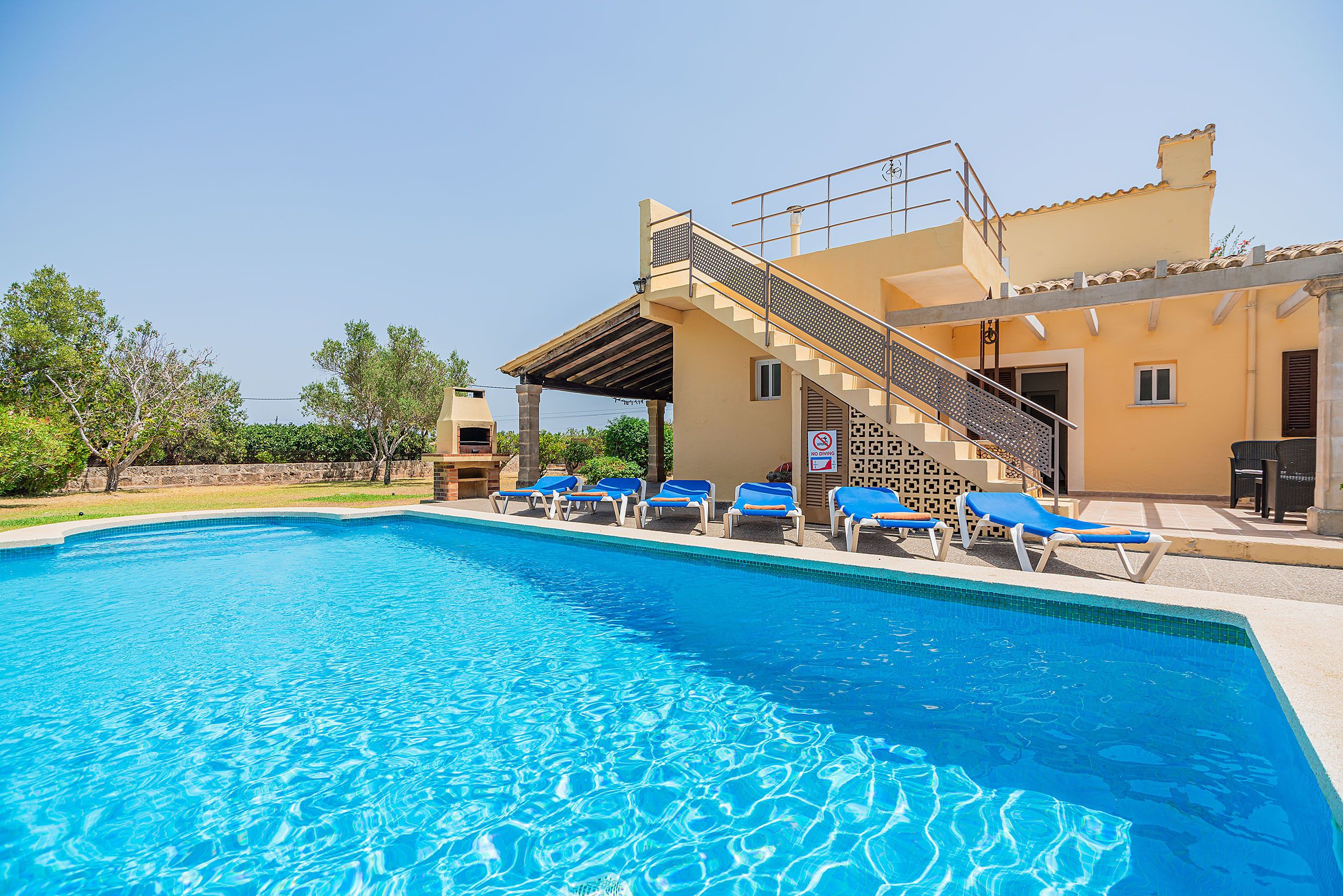 En swimmingpool med liggestole og en trappe op til en bygning.
