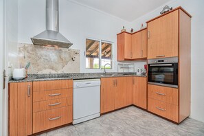 A kitchen with wooden cabinets, a dishwasher, a stove, and a window with a view. - Villa Sureda - By Dream Villas Pollensa (Pollensa)