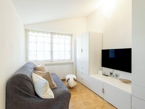 Ein modernes Wohnzimmer mit einer Couch, einem Fernseher und einem Kleiderschrank.