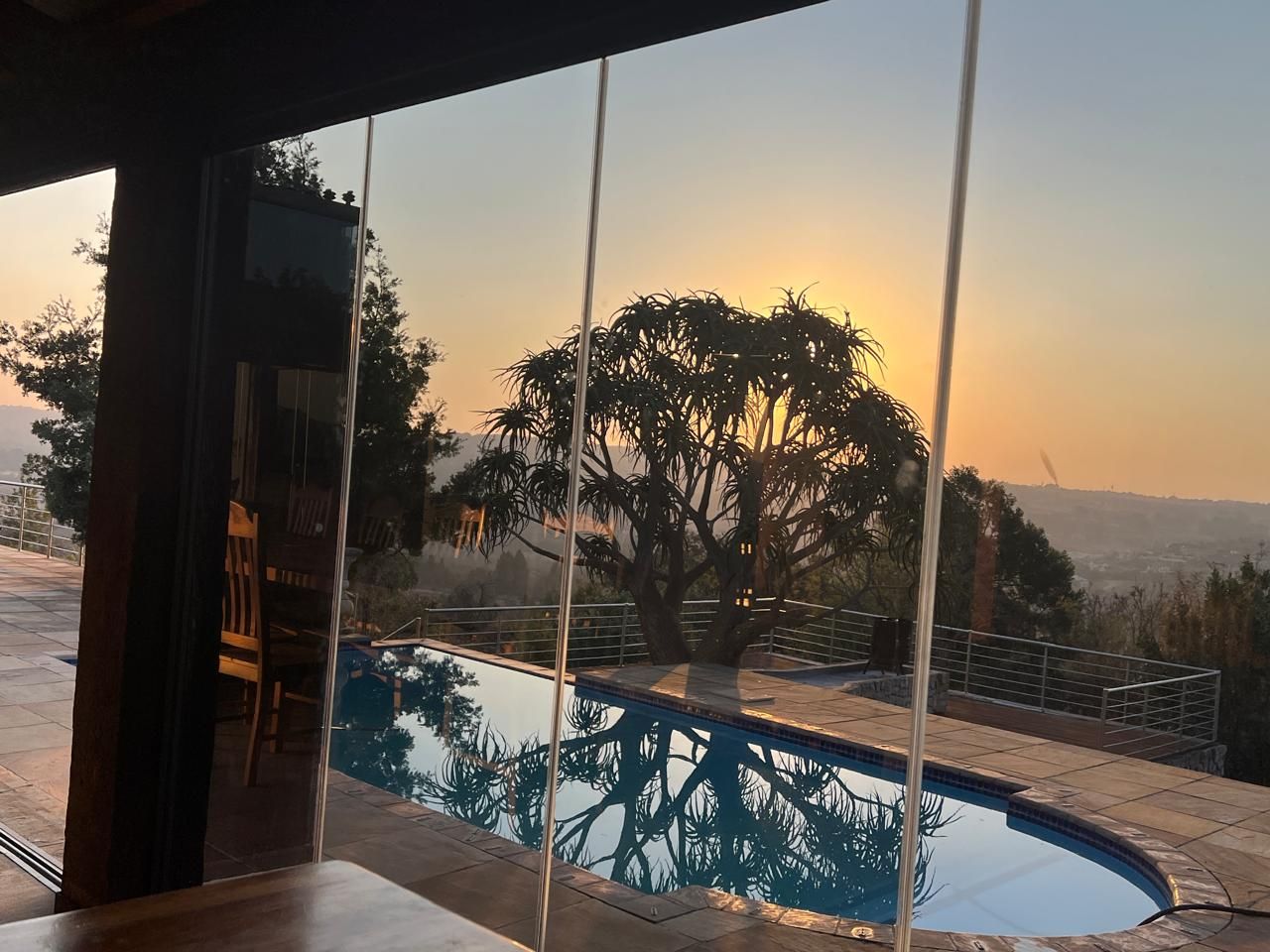 A pool with a view of a tree and a sunset.