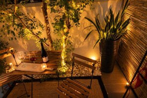 An outdoor seating area with a table, chairs, a bottle of wine, glasses, and a candle. - Urban Purple by Domisi with Jacuzzi (Rethimno)