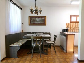 A dining area with a bench, table, chairs, and a painting on the wall. - Ca' Angiulin by Interhome (Olivone)